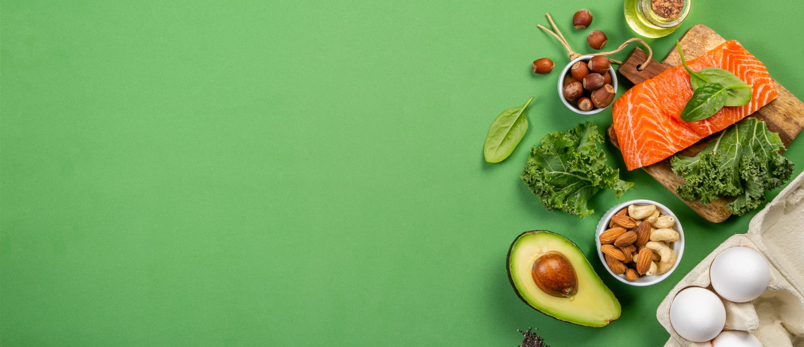 Fresh salmon, kale, avocado and nuts on a green background